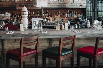 Wooden bar counter with defocus background and bottle of restaurant, bar, cafeteria. Prepare the set of glasses, fork and knife on the table