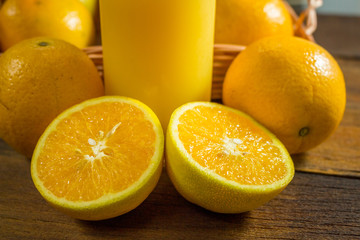 Some oranges in a basket on wooden background.