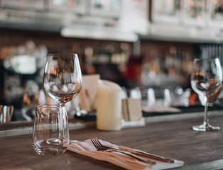 Empty glasses in the restaurant with knife and fork on wooden table, waiter prepare table to we;come customer