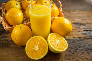 Some oranges in a basket on wooden background.