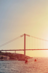 View of ferry and tour boats on Bosphorus in Istanbul. The bridge is also in the view. Sunset light effect is applied.