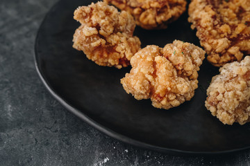 Chicken karaage japanese food in the black plate on grey concrete background with herb and flour