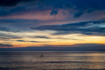 Fishermen on a canoe in the ocean at sunset/sunrise