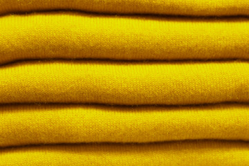 Fototapeta na wymiar Stack of trend Ceylon yellow woolen knitted sweaters close-up, texture, background