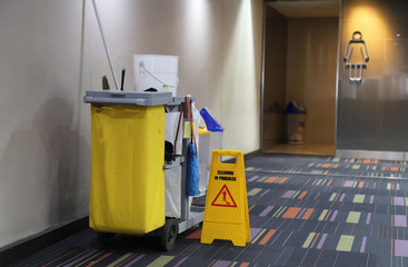 Closeup of cleaning equipment and tools for floor cleaning in front of woman WC.