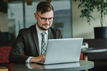 Young successful businessman working on a laptop while sitting in cafe. 