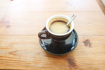 Coffee cup of Espresso Americano in black mug ceramic on the soft brown wood table background with flare