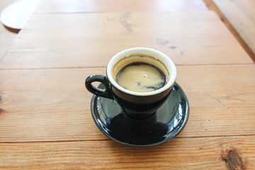 Coffee cup of Espresso Americano in black mug ceramic on the soft brown wood table background