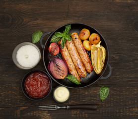 grilled, juicy sausages in a pan on a wooden background