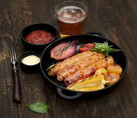 grilled, juicy sausages in a pan on a wooden background
