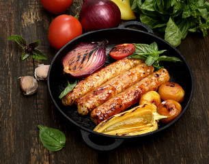 grilled, juicy sausages in a pan on a wooden background