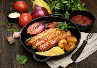 grilled, juicy sausages in a pan on a wooden background