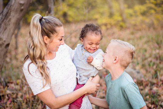 Beautiful candid portrait of a mother playing with her cute children. Mother and her two boys spending time together in the outdoors and laughing together. Great adoption or blended family photo