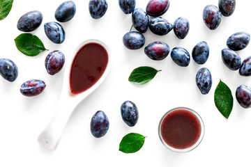 Fresh tkemali sauce. Traditional caucasian, georgian sauce or plum jam in spoon near plums on white background top view