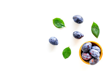 Blue plum for dessert. Purple plum and leaves pattern on white background top view copy space