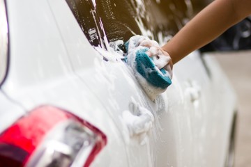 Use your right hand to catch the sponge and polish the car window. Concept car wash.