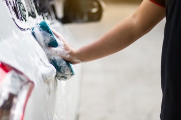 Hands hold with blue sponge washing car. Concept car wash clean.