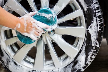 This image is a picture of wiping the car with a blue microfiber cloth by hands.Car wash concept.