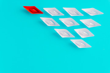 White and red paper boat or ship in one direction on blue background. Business for innovative solution concept with selective focus