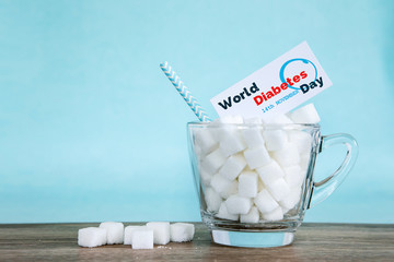 White sugar cube in a glass on wooden table with light blue background , unhealthy sweet food concept for 14th November campaign of World Diabetes Day