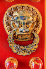 Red wooden door fragment with a lion figurine knocker in the Forbidden City Beijing