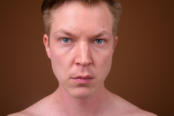 Naklejka premium Portrait of young man face against brown background