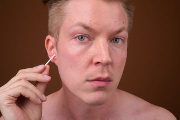 Portrait of man cleaning his ears wax with cotton swab