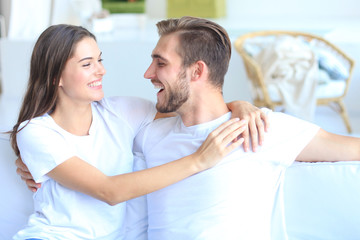 Happy young couple hugging and looking at each other at home interior.