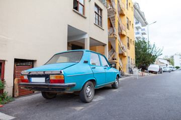An old blue car stands on a street