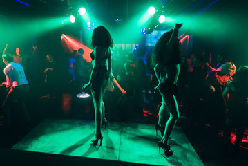 dancers dancing go-go on stage in a nightclub. Silhouettes of protruding girls - obrazy, fototapety, plakaty