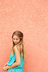 Beautiful blond girl by wall, looking down