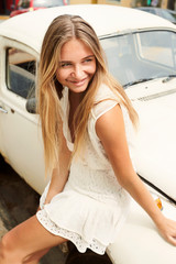 Beautiful young woman on white car, looking away