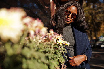 Fototapeta premium Stylish african american girl in blue coat and sunglasses posed at sunny autumn day. Africa model woman.
