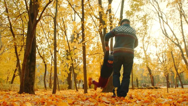 Grandfather playing with his grandson in the autumn park
