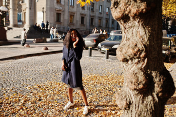 Stylish african american girl in blue coat posed at sunny autumn day. Africa model woman.