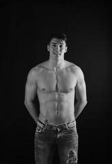 Fototapeta na wymiar portrait of young man with torso naked with jeans on black background