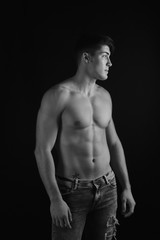 Fototapeta premium portrait of young man with torso naked with jeans on black background