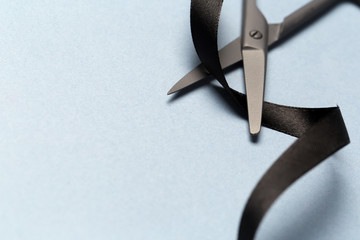 Grand Opening illustrated with  scissors and a black ribbon on a gray background