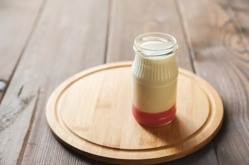 Milk yogurt in a jar of red raspberry or strawberry layer on a round wooden board