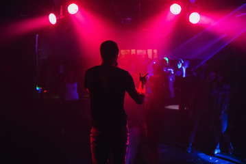 Fototapeta na wymiar mc with microphone on the night club scene on the background of blurred dancing people