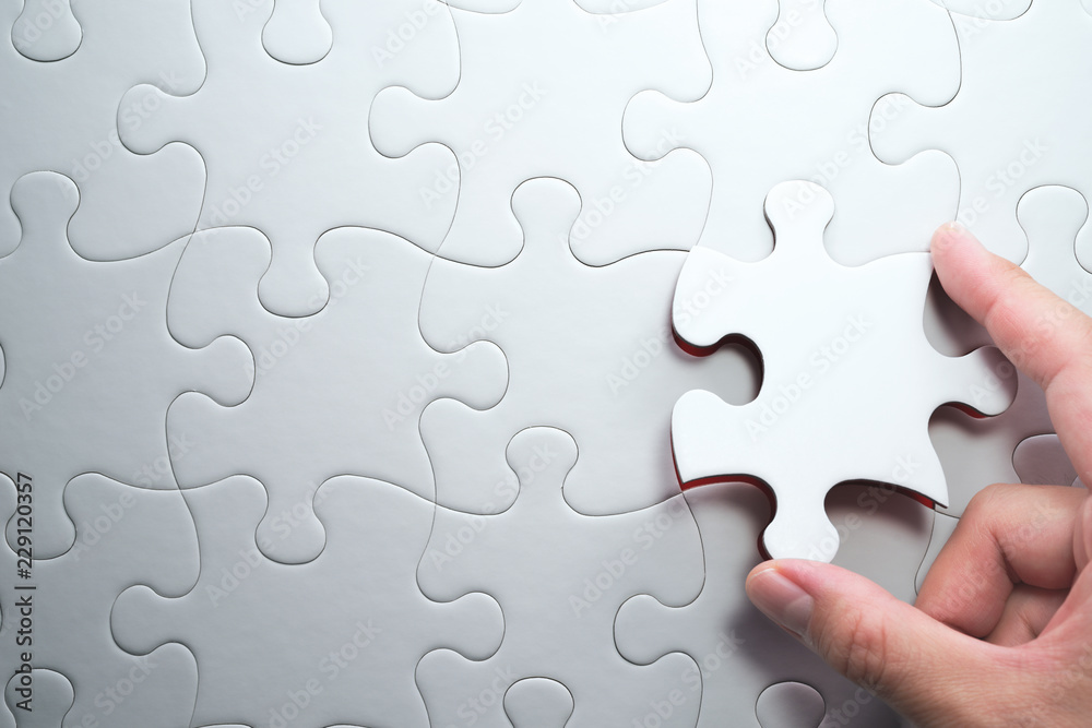 Fototapete Putting last jigsaw puzzle piece. Solving and completing the task.The correct solution. Assembling white jigsaw puzzle pieces.