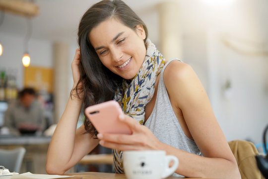 Brunette woman in coffee shop using smartphone