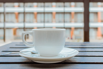 Empty a cup of coffee on saucer with coffee spoon isolated on wooden table that it is on terrace in...
