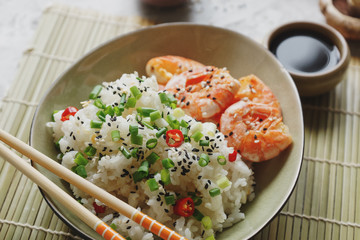 Teppanyaki fried rice with shrimp, mushrooms, green onion, pepper and herbs on light concrete background, asian food, healthy lifestyle concept, selective focus