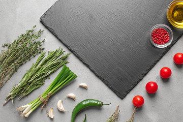 Flat lay composition with fresh herbs and slate plate on grey background