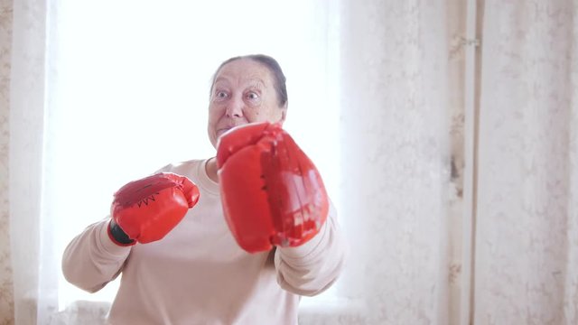 Portrait of old senior woman having fun and smiling while boxing