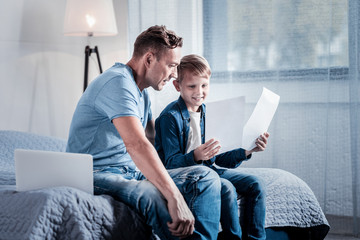 What the difference. Interested caring attentive father sitting in the bedroom spending time with...
