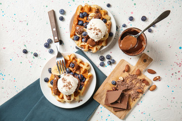 Delicious waffles with banana slices, blueberries and ice cream on light table