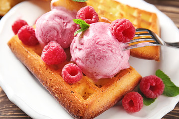 Delicious waffles with raspberries and ice cream on plate, closeup