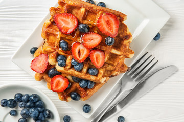 Delicious waffles with berries on plate